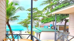 A balcony with wooden furniture, a view of the beach, and a pool. - Globiquex Hotels (Duong Dong)