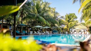 A pool area with lounge chairs and umbrellas, surrounded by palm trees. - Globiquex Hotels (Duong Dong)