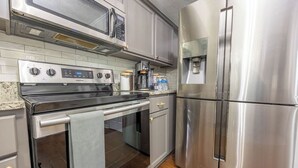 Une cuisine moderne équipée d’appareils électroménagers en acier inoxydable, notamment une cuisinière, un four, un four à micro-ondes et un réfrigérateur.