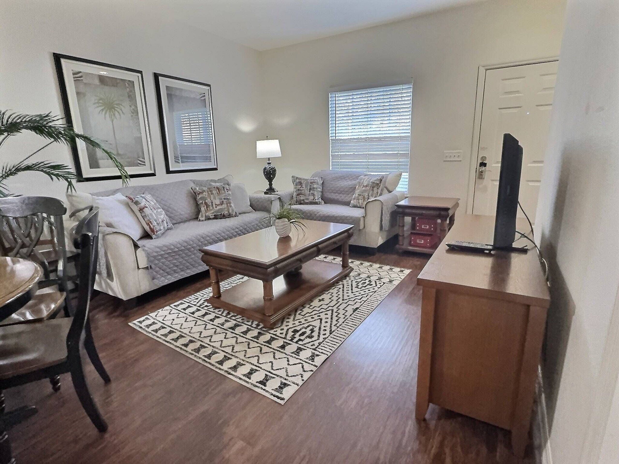 Una sala de estar con sofá, mesa de centro y mueble para televisión.