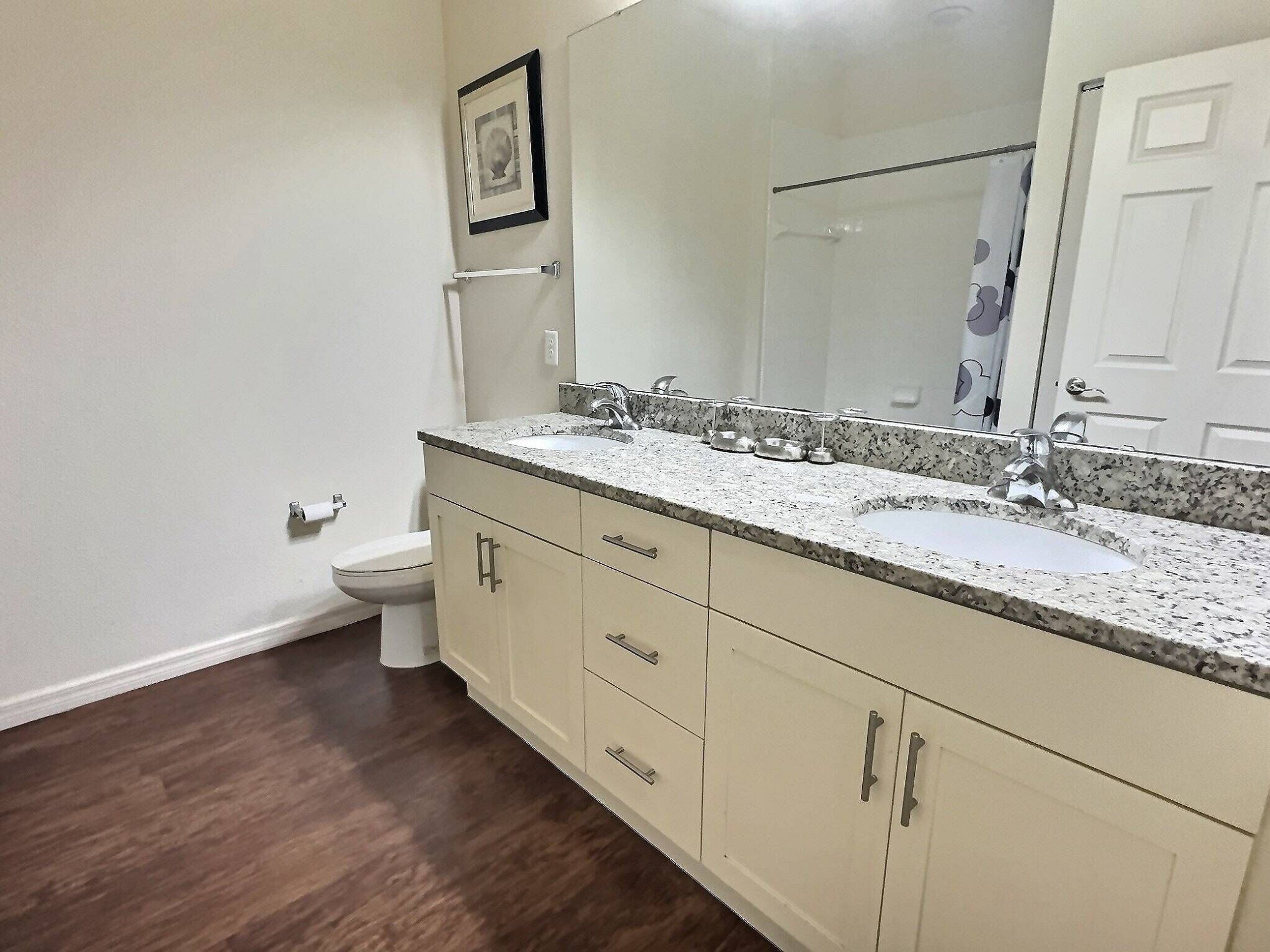 A bathroom with two sinks, a toilet, and a large mirror.