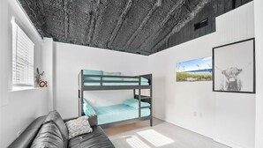 Ett modernt, minimalistiskt rum med en våningssäng, en soffa i läder och en inramad tavla på väggen.