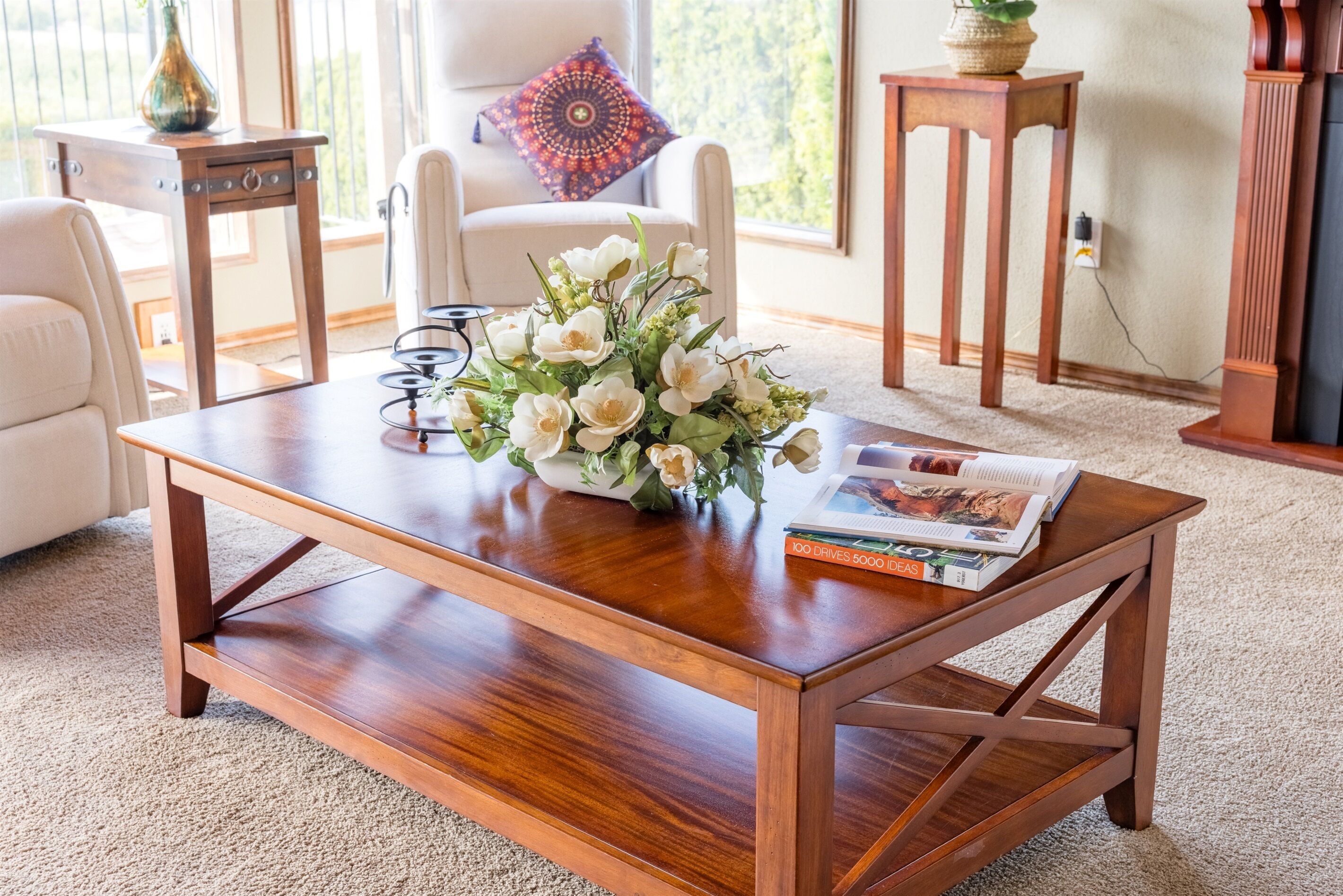 A wooden coffee table with a vase of white flowers and a magazine.