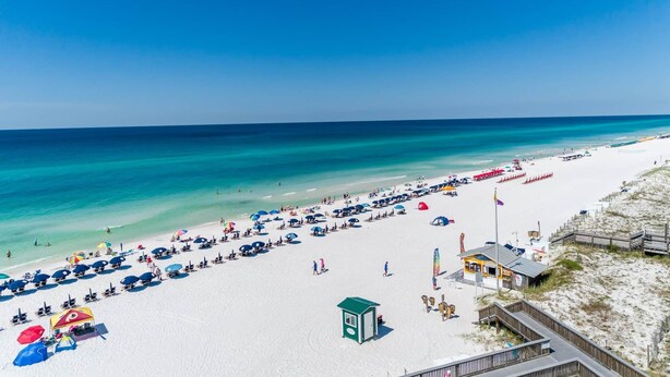 A beach with white sand, clear blue water, and a lifeguard station. - Luxury 4BR/4.5BA Waterfront Home in Sandestin • Golf Carts/Golf • Pool • Beach (Miramar Beach)