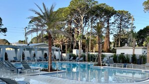 A pool area with lounge chairs and palm trees. - Luxury 4BR/4.5BA Waterfront Home in Sandestin • Golf Carts/Golf • Pool • Beach (Miramar Beach)