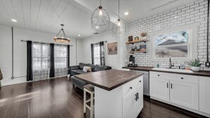 Een moderne keuken met witte kasten, een houten keukeneiland en hanglampen.
