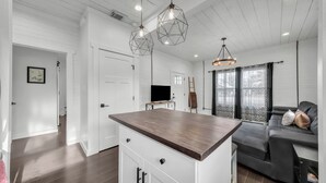 Een moderne keuken met een centraal eiland, hanglampen en een zithoek met een bank.