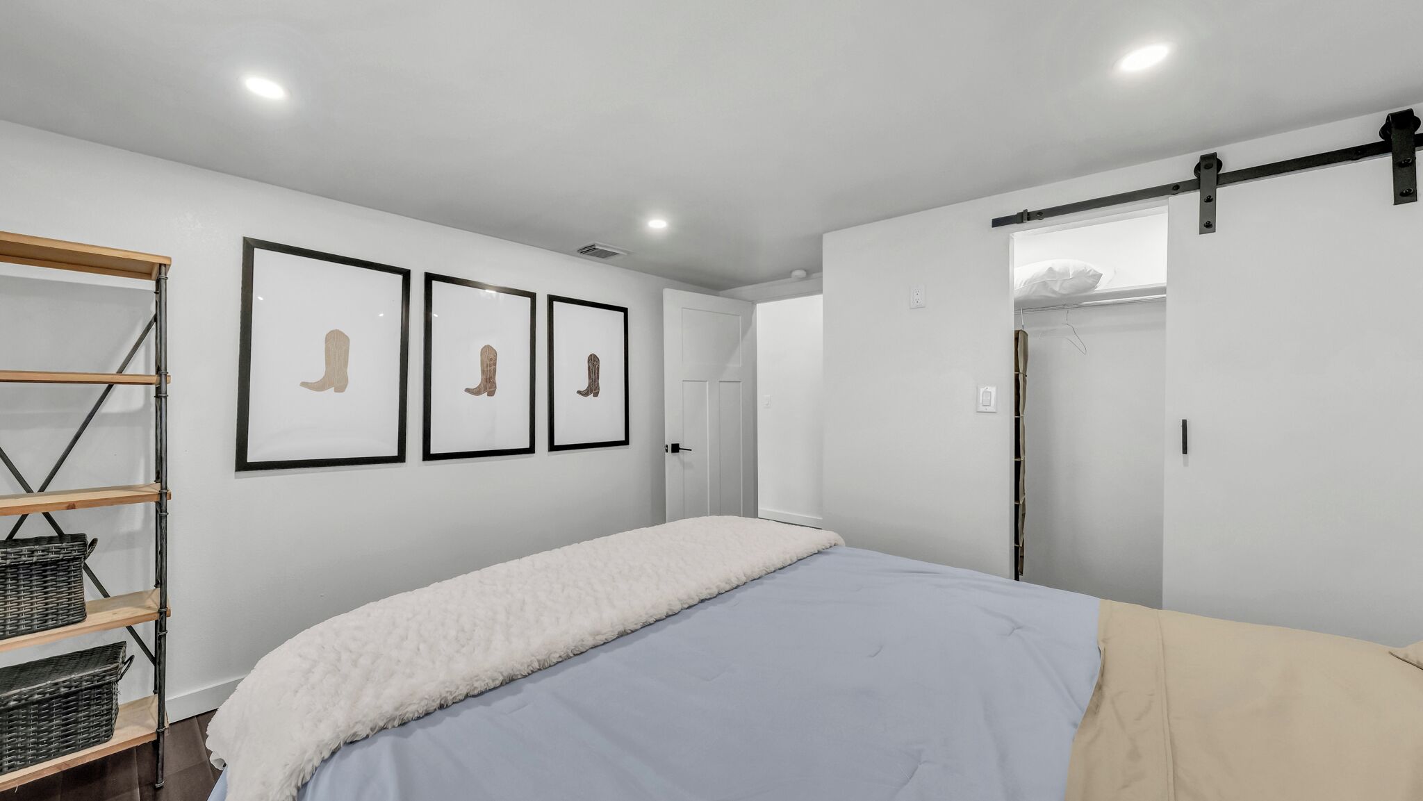 A bedroom with a bed, a wardrobe, and three framed pictures on the wall.
