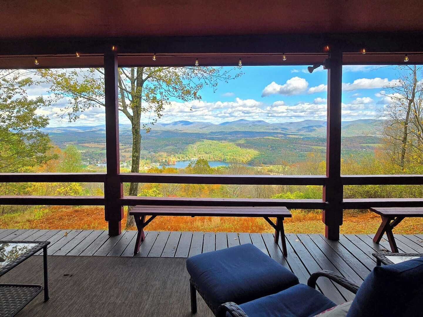 Un espace extérieur abrité, aménagé avec des sièges, et offrant une vue sur un lac et des montagnes.