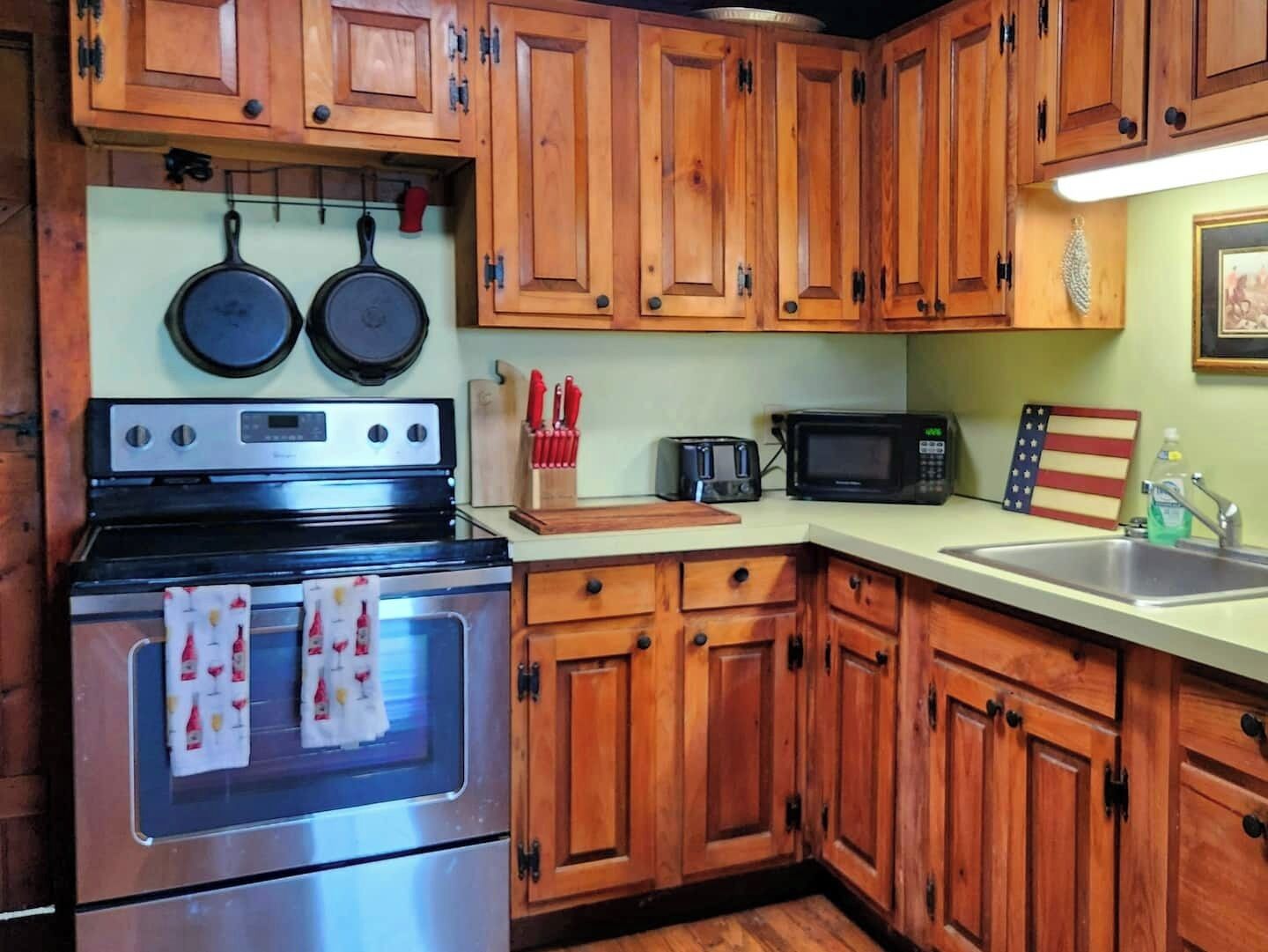 A kitchen with wooden cabinets, a stove, a microwave, and a sink.
