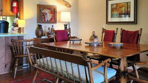 Un coin repas avec une table en bois, des chaises, un extincteur, une lampe, un vase et un tableau accroché au mur.