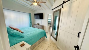 A bedroom with a bed, a nightstand, a TV, a sliding door, and a ceiling fan. - Intracoastal house w/Boat Lift in Treasure Island (Treasure Island)