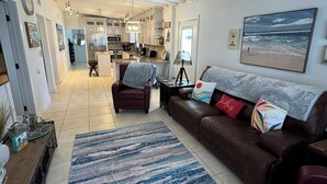 A spacious living room with a brown leather sofa, a patterned rug, and a ceiling fan. - Intracoastal house w/Boat Lift in Treasure Island (Treasure Island)