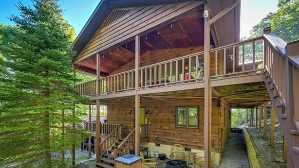 Uma cabana de registos com dois andares, varanda, deck de madeira e área de estar exterior.
