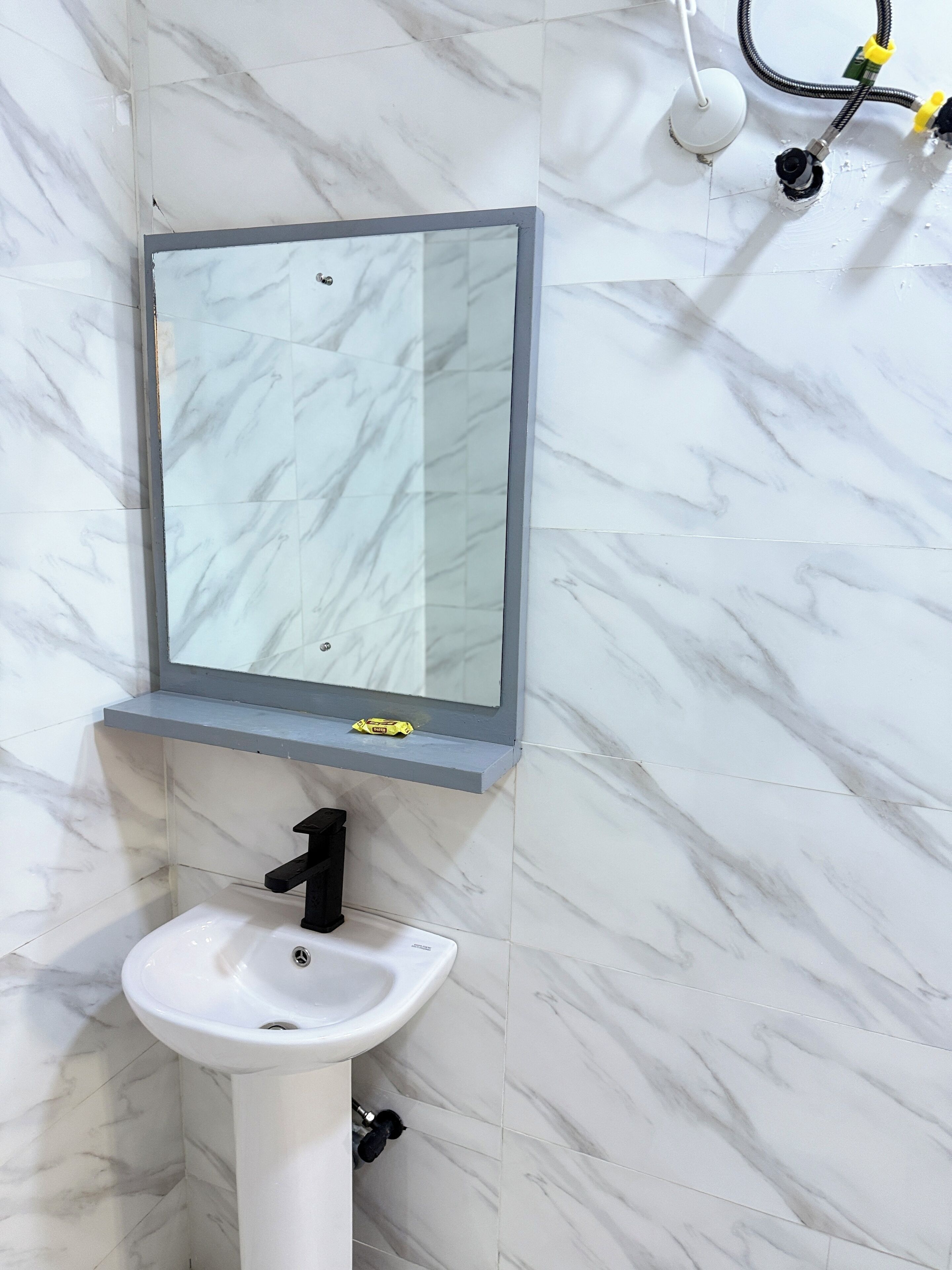 Un baño con un lavabo blanco, un espejo y una pared con diseño de mármol.