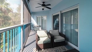 Un balcone con ventilatore a soffitto, mobili in vimini e vista sull'esterno.