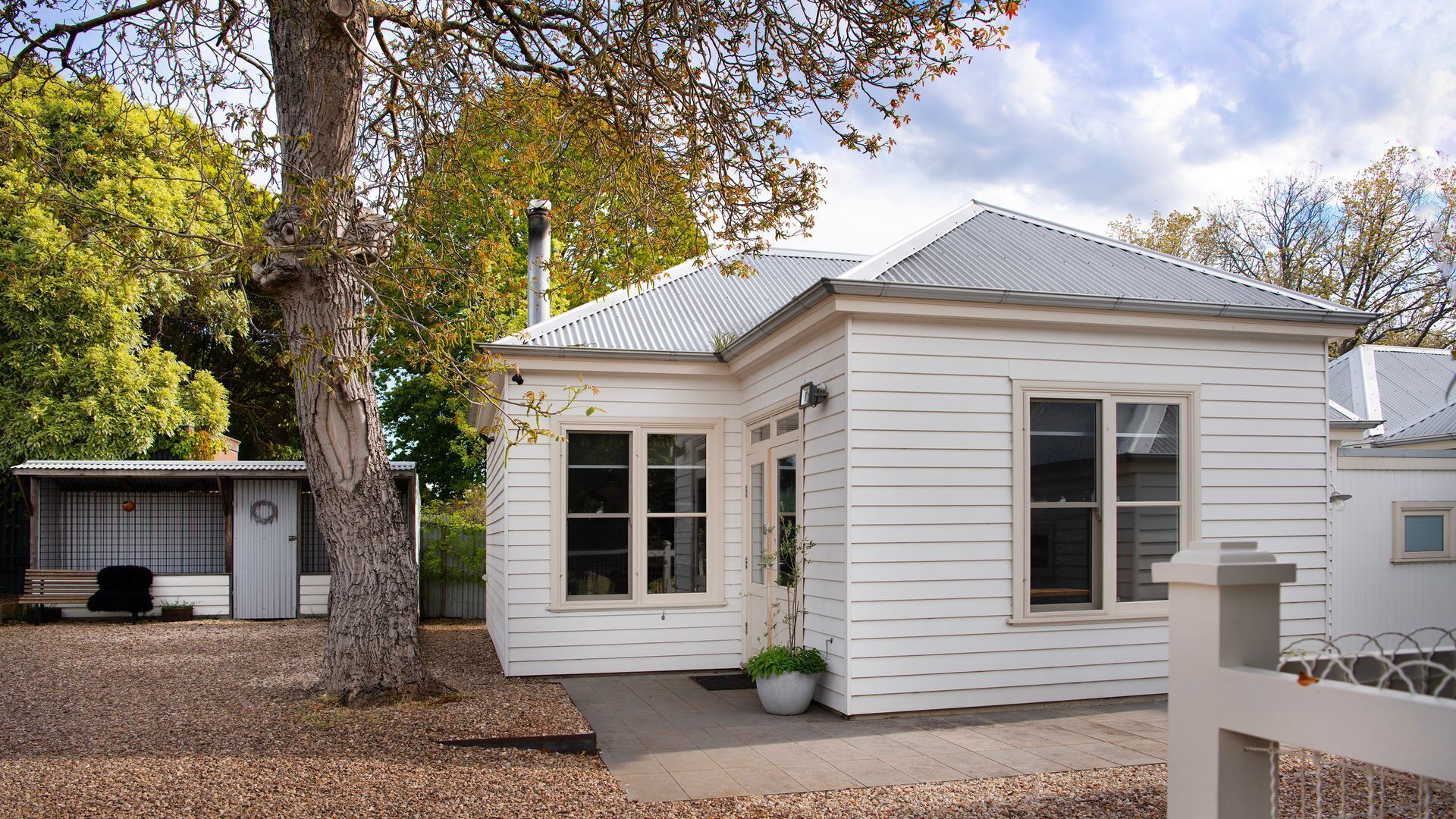A small, single-story house with a sloped roof, large windows, and a front porch.