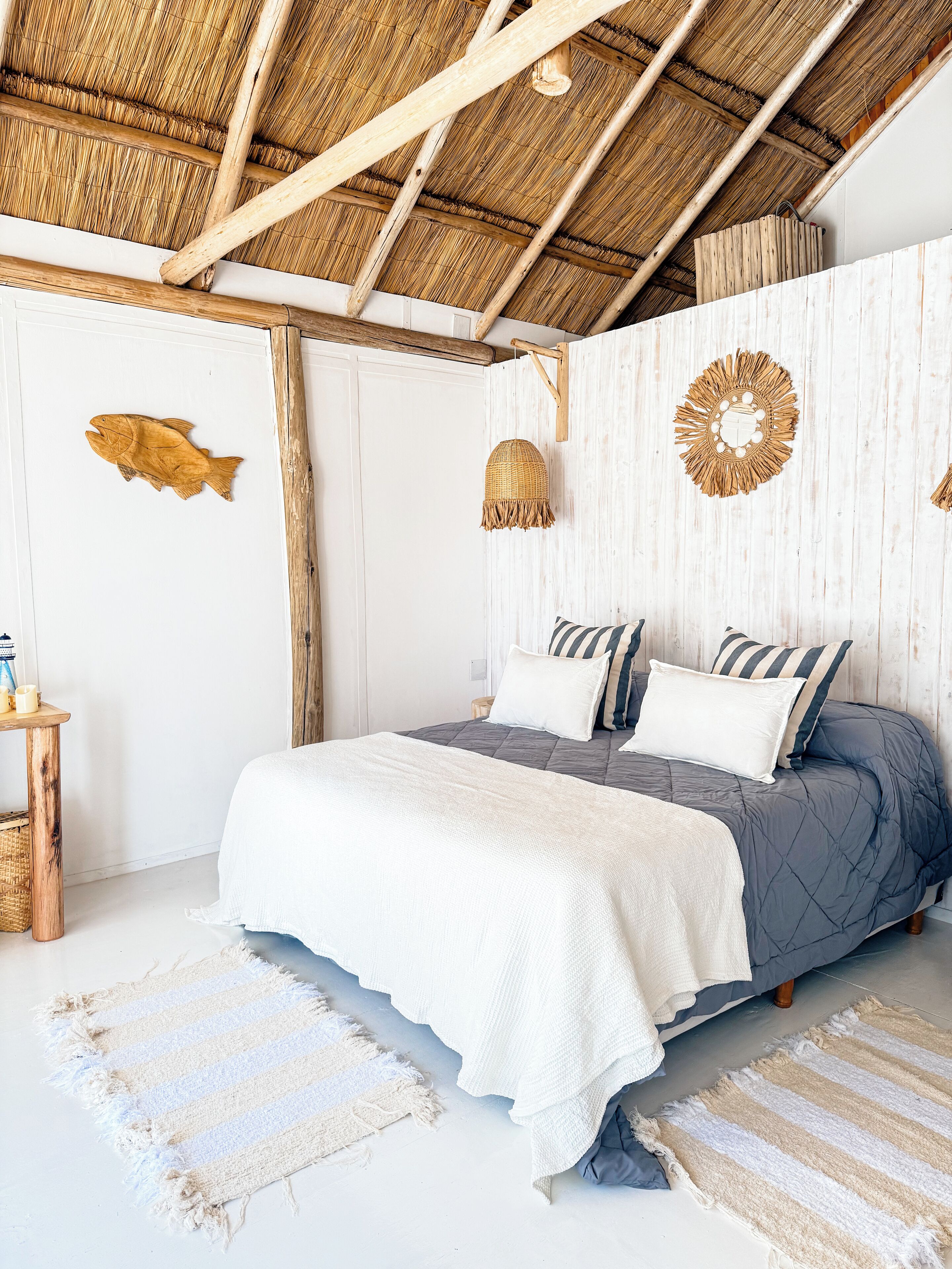 Une chambre à coucher avec un lit, des oreillers, une table de chevet, une lampe et un élément décoratif mural.