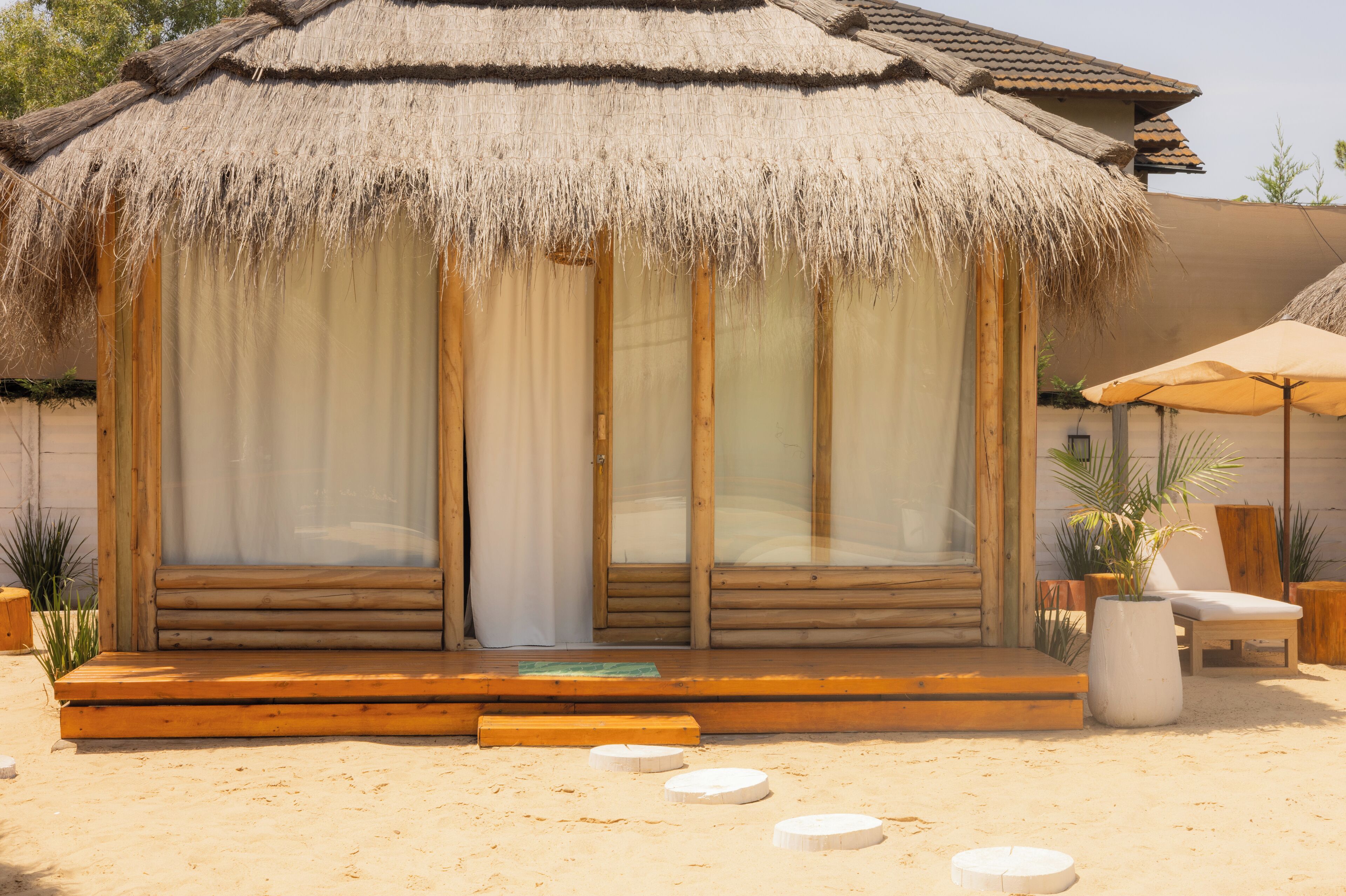 A wooden structure with a thatched roof, large windows, and a wooden deck.