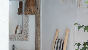 A bathroom with a wooden vanity, a mirror, a woven light fixture, and a wooden ladder leaning against the wall. - Tribu Eco Beach (Francisco Alvarez)