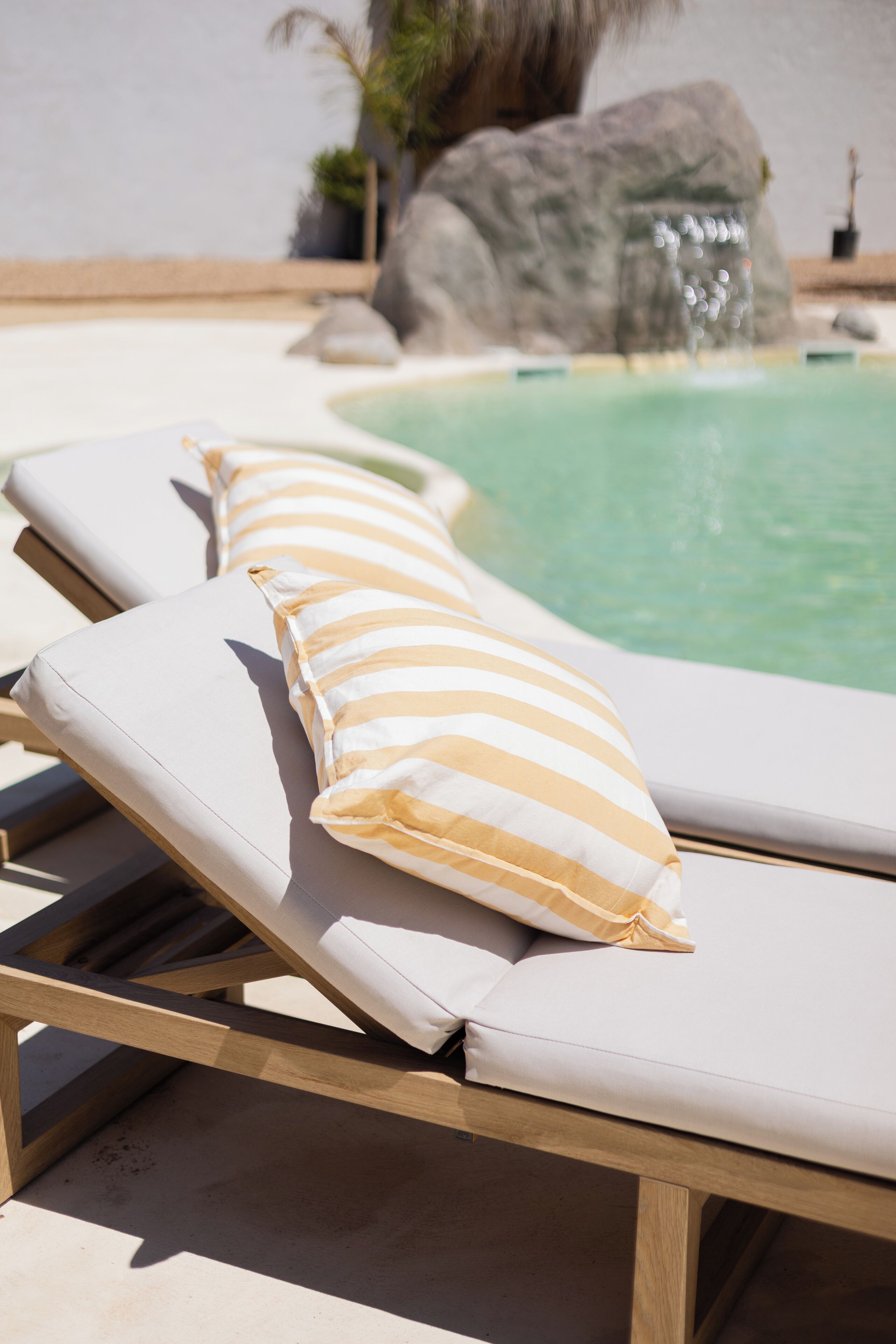 A poolside area with lounge chairs and a large rock formation in the background.