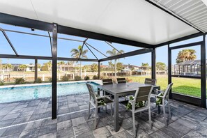 A covered patio area with a pool, outdoor seating, and a view of the surrounding landscape. - Villa Capri -  Waterfront Retreat with Heated Pool (Punta Gorda)
