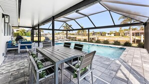 Ein überdachter Außenbereich mit Pool, Sitzgelegenheiten und Blick auf die umliegende Landschaft.