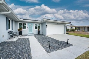 A modern two-story house with a light blue door, a front bench, and a gravel driveway. - Villa Capri -  Waterfront Retreat with Heated Pool (Punta Gorda)