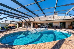 Una piscina con tetto in vetro, lettini e una zona salotto coperta.