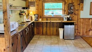 Una cocina rústica con armarios de madera, una ventana, un fregadero, un microondas y un lavavajillas.