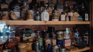 A wooden shelf with various antique bottles and containers, some labeled with names and others with dates. - Beautiful, Quaint, and Cozy Rooms. (Wolf Creek)