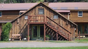 A wooden cabin with a porch and a staircase leading to the entrance. - Beautiful, Quaint, and Cozy Rooms. (Wolf Creek)
