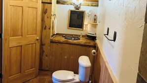 A compact bathroom with a wooden vanity, a toilet, and a sink.