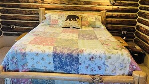 Un llit amb un llençol floral, un capçal de fusta i un coixí amb un disseny d'ós.