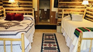 Habitació d'estil cabana amb dos llits de fusta, una porta central i una catifa amb dibuixos.