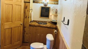 Un bany compacte amb un penjador de fusta, un vàter i un petit lavabo.