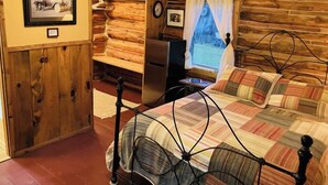 Habitació tipus cabana de fusta, amb un llit, un escriptori i un ordinador portàtil.