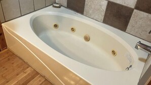 Una banyera gran i rectangular amb tres aixetes i un únic vàter.