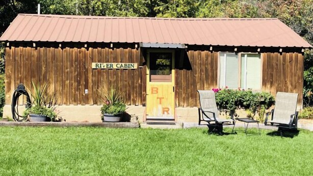 A small cabin with a sign reading "RIVER CABIN" and a door marked "BTR". - Beautiful and Quaint Cabin  (Wolf Creek)