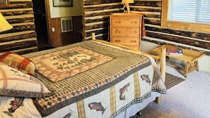 Een knus ingerichte kamer met een bed, een houten dressoir en een klein houten tafeltje.