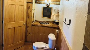 Een compacte badkamer met een houten wastafelmeubel, toilet en wastafel.