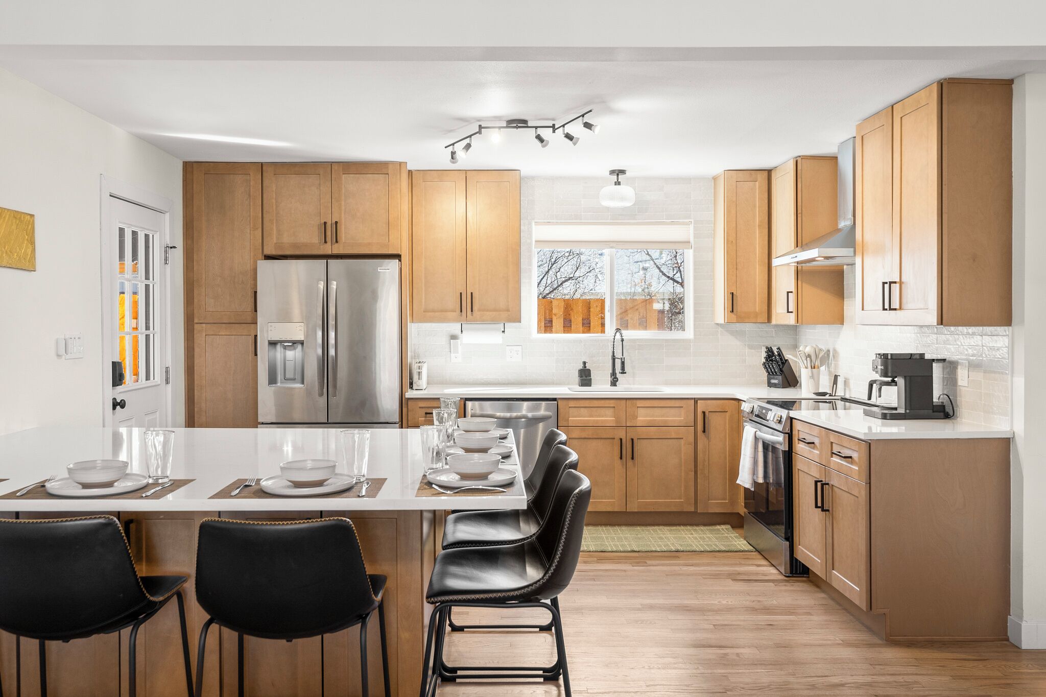 A modern kitchen with wooden cabinets, stainless steel appliances, and a central island with bar stools.