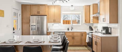 A modern kitchen with wooden cabinets, stainless steel appliances, and a central island with bar stools.