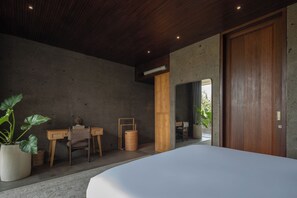 Ein Schlafzimmer mit einem großen Bett, einem Holztisch, Stühlen und einer Topfpflanze.