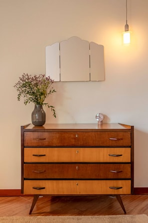 A wooden dresser with multiple drawers and a vase of flowers on top. - Spacious Saldanha Flat w/ Private Deck, Near Metro (Lisboa)