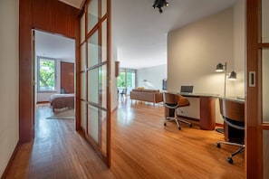 A spacious room with a wooden floor, a desk with a computer, a sofa, and a chair. - Spacious Saldanha Flat w/ Private Deck, Near Metro (Lisboa)