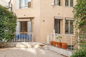 A residential building with a brick facade, a balcony with blue chairs, and potted plants. - Spacious Saldanha Flat w/ Private Deck, Near Metro (Lisboa)