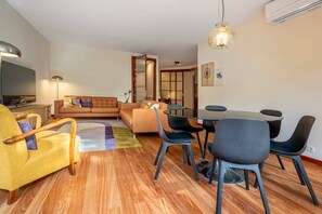 A modern living room with a sofa, chairs, a dining table, and a TV. - Spacious Saldanha Flat w/ Private Deck, Near Metro (Lisboa)