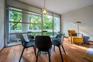 A modern dining area with a glass table, black chairs, and a yellow armchair. - Spacious Saldanha Flat w/ Private Deck, Near Metro (Lisboa)