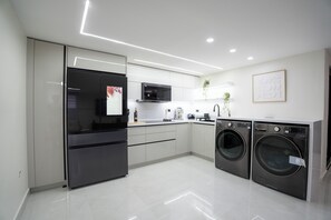 A modern kitchen with stainless steel appliances, white cabinetry, and a built-in washer and dryer. - Modern Cozy Apt Just Steps from the Beach (Crolina)